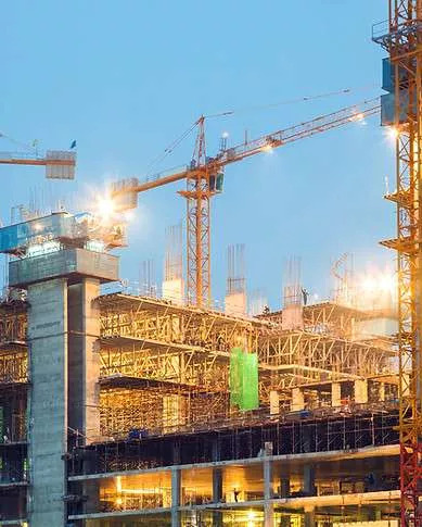 Canteiro de obras com gruas ao anoitecer